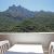 Une vue magnifique des montagnes verdoyantes depuis un balcon avec une table et des chaises blanches.