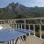 Balcon avec une table bleue, des chaises blanches et une vue magnifique sur les montagnes verdoyantes.